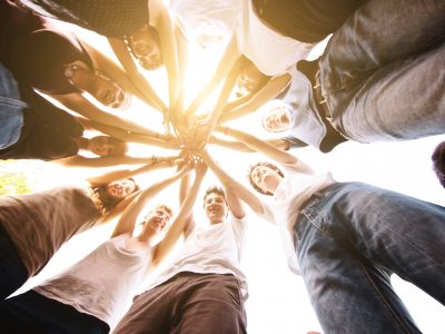 Group of friends holding hands together making a circle