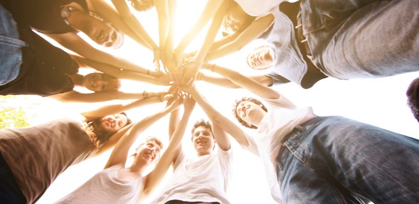Group of friends holding hands together making a circle