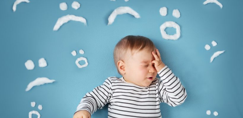 uhappy little boy on blue blanket background with sad smiley faces