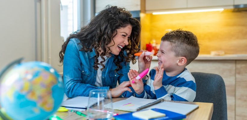 Mother helping with homework to her son indoor. Family, children and happy people concept. Mother and sons drawing together, mom helping with homework